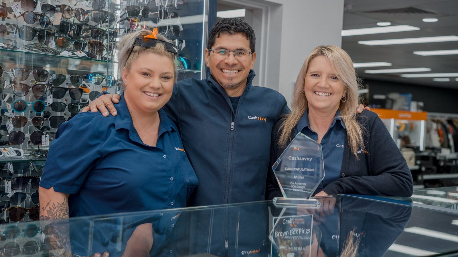 Cash Savvy team members in branded navy uniform shirts in store