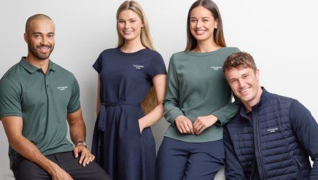 Four staff wearing branded corporate polo shirts and a navy work dress