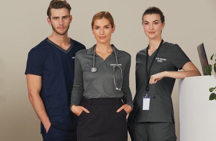 Three healthcare workers in branded scrubs and lanyards
